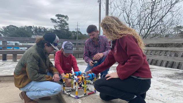 Students and teachers fixing a PVC frame with floats